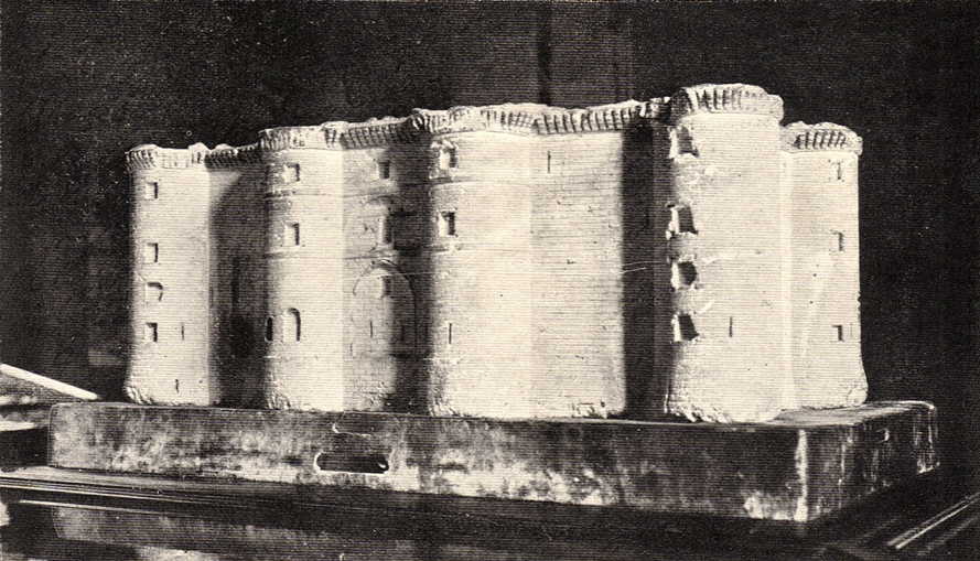 A black and white old photograph of a model of the Bastille, by the instructions of the architect Palley, a rectangular brick building with 4 towers on one side connected by a wall of the same height.