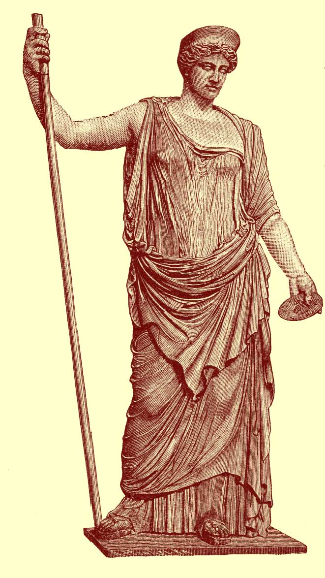 Black and white photograph of a full-length statue of Hera (Juno), the goddess, with wavy hair, crowned, holding a long staff in one hand and a flst round disc in the other, from the Vatican in Rome, Italy.