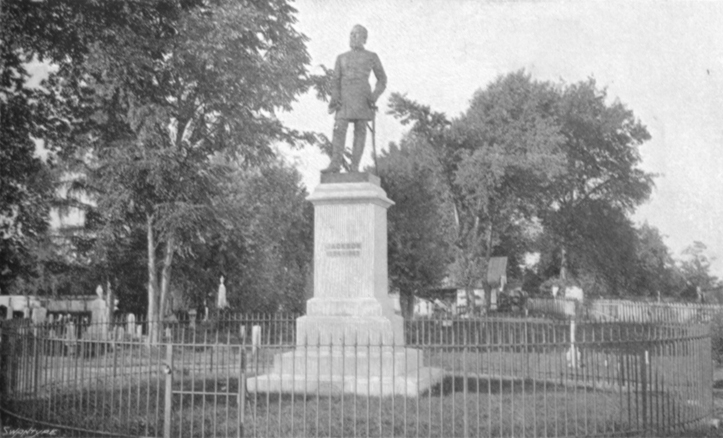 Black and white photograph of the grave of Stonewall Jackson, with a statue of him in uniform, in Lexington, Va.